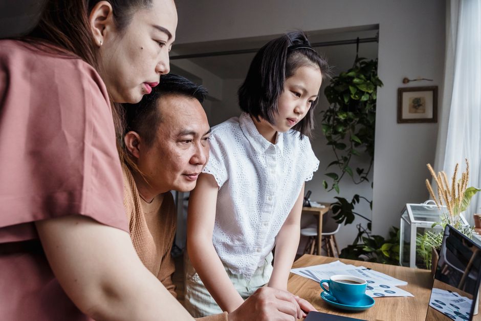 中年父母與成年子女在餐桌前討論房貸文件的情境畫面